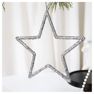Silver glitter star Christmas tree ornament hanging on a pine branch in soft light