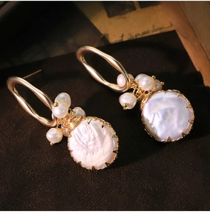 Close-up of vintage baroque pearl earrings with golden metal borders and tiny pearls