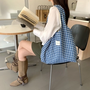 Blue and white checkered woven tote bag shown in a lifestyle indoor setting