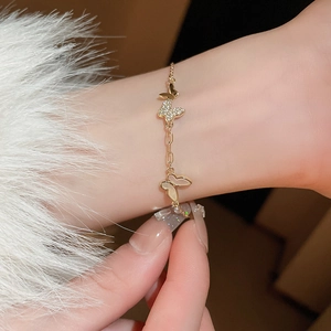 Detailed view of a gold-plated bracelet featuring butterfly charms with zircon and mother of pearl