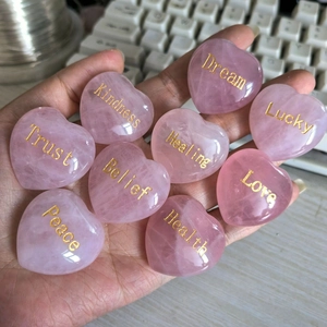 Nine pink rose quartz heart stones with gold engraved inspirational words held in hand