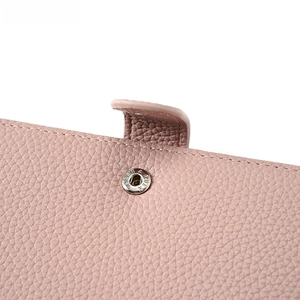 Detailed macro view of pink litchi grain leather passport wallet with metal snap closure