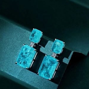 Detail of drop earrings with emerald-cut Paraiba blue stones in silver claw setting