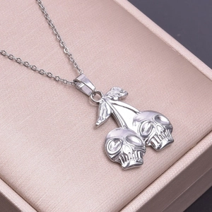 Macro shot of silver stainless steel necklace with twin skull cherry pendant detail