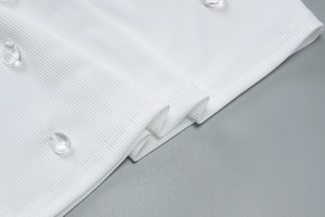 Close-up of white ribbed knit fabric with delicate bead embellishments and fine stitching