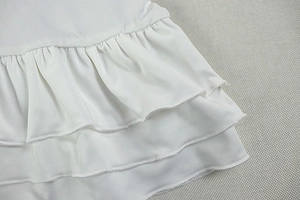 Close-up of white layered ruffle details and precision stitching on a sleeveless dress