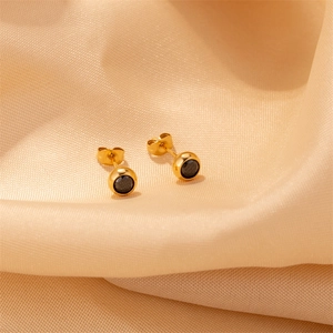 Classic round gold titanium steel stud earrings with black zircon on champagne silk background