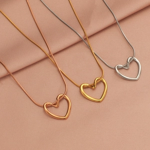 Three heart pendant necklaces in rose gold, gold, and silver on pink silk fabric