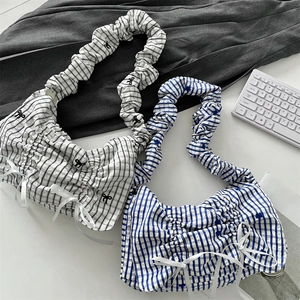 Close-up of pleated straps and bow detail on blue and black checkered shoulder bags
