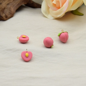 Artistic layout of pink peach resin pendants with green leaves on textured fabric background