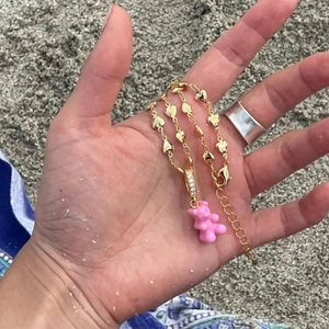 Detailed close-up of a pink resin gummy bear pendant on a gold heart chain necklace