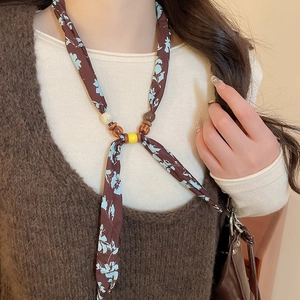 Close-up of floral silk scarf necklace featuring dark brown patterns and wooden beads