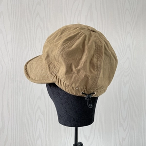 Detail of khaki nylon baseball cap featuring adjustable black toggle drawstring for size fit