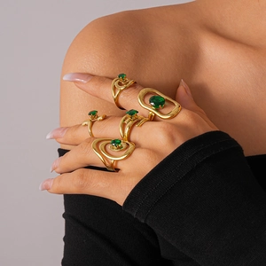 Detail of gold-plated vortex rings set with emerald green zircon on model hand