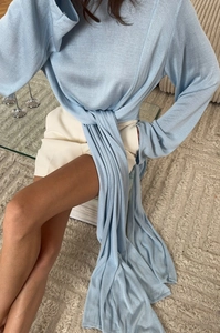 Dettaglio del top in maglia azzurro con lacci in vita e consistenza del tessuto morbido