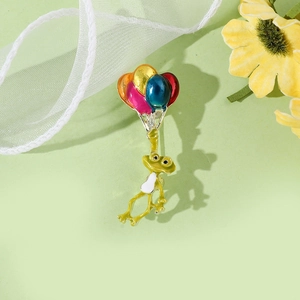 Détail d'une broche en émail grenouille mignonne avec ballons colorés et fini brillant