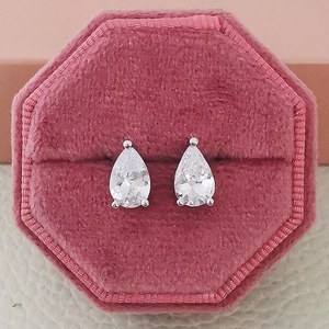Close-up of pear-shaped zircon earrings in a pink velvet jewelry box showing detail