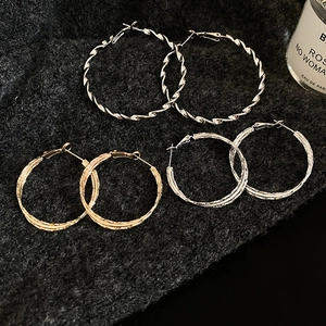Flat lay of assorted gold and silver twisted hoop earrings with textured finish detail