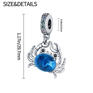 Close-up of silver crab charm with blue gemstone inlay and detailed size measurements