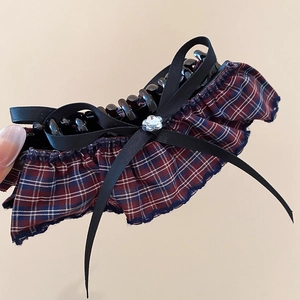Detail of a vintage acrylic hair claw with black bows and red-blue plaid fabric edges