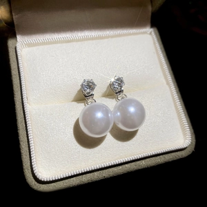 Macro shot of elegant silver pearl earrings with sparkling cubic zirconia on velvet