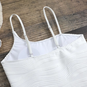 Close-up of white one-piece swimsuit fabric with wavy texture and adjustable straps