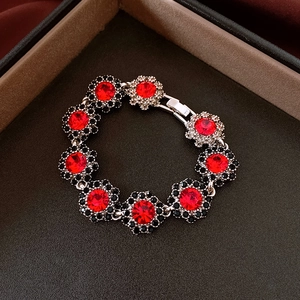 Detail of silver floral bracelet with large red gems and black accents in a jewelry box