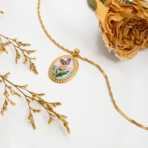 Collier doré vintage avec pendentif tulipe papillon et perle sur fond blanc