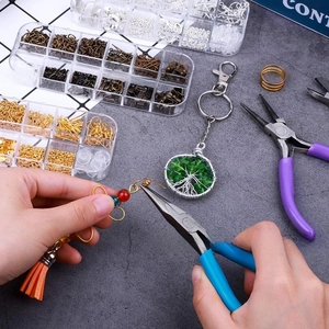 Overhead view of jewelry making kit with colorful metal rings and needle-nose pliers