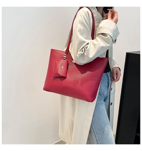 Detail of red leather tote bag showing grainy texture and golden snap button detail