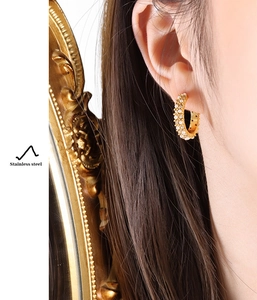 Détail des boucles d'oreilles en C en acier doré 18K avec incrustations de perles