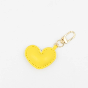 Detail of a yellow heart-shaped leather keychain with a premium golden metal clasp