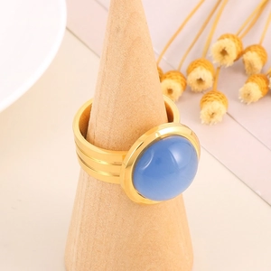 Macro view of a gold-layered ring featuring a round blue gemstone on a wooden display