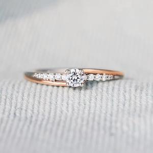 Minimalist two-tone geometric ring with round diamond and pavé accents on fabric background