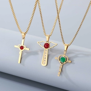 Detailed view of three gold cross necklaces with red and green gems on a display