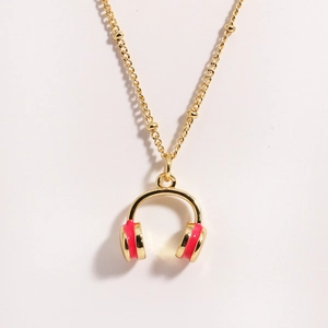 Detail of golden mini headphone pendant with red enamel on a stylish bead chain necklace