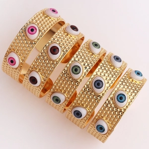 Détail de charms œil protecteur sur bracelets ouverts dorés texturés en cinq couleurs