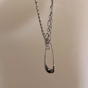 Detail showing the silver safety pin pendant with a smooth industrial metal finish