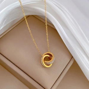 Detailed view of interlocked gold circles necklace with crystals on beige silk fabric