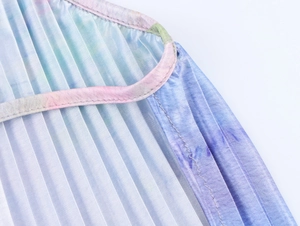 Vue macro du tissu plissé tie-dye avec dégradé de couleurs et détails satinés