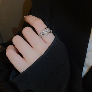 Sparkling multi-layer crisscross ring with zircons shown on hand against black background