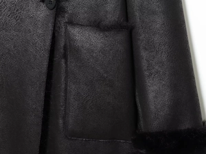 Detailed macro view of black faux fur coat texture, button closure and pocket stitching