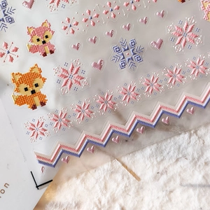 Thin pixel art nail stickers with fox and snowflake motifs in warm orange and pink tones