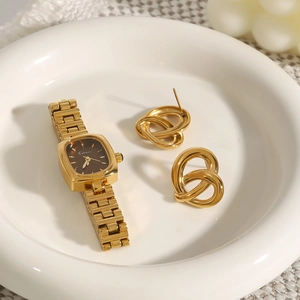 Golden square watch with brown dial and twisted knot earrings on white ceramic tray