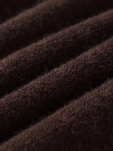 Macro shot of dark brown knit fabric with thick wool texture and detailed weaving pattern