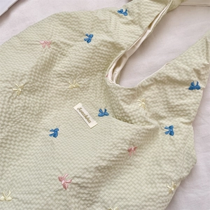 Détail du sac seersucker avec nœuds brodés colorés et étiquette de marque en tissu