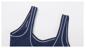 Detailed close-up of dark blue sports bra showing U-neckline and white contrast stitching