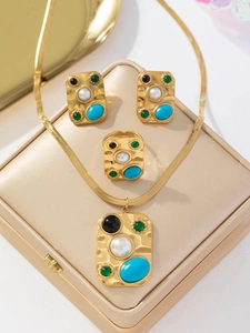 Parure de bijoux dorés avec pierres carrées colorées et perles sur boîte beige