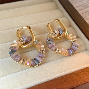 Detailed macro of gold baroque hoop earrings with purple crystals and sparkling rhinestones