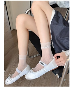 Detail of white ballet flats with bow and sheer socks featuring delicate embroidery